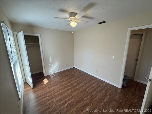 an empty room with wooden floor and fan
