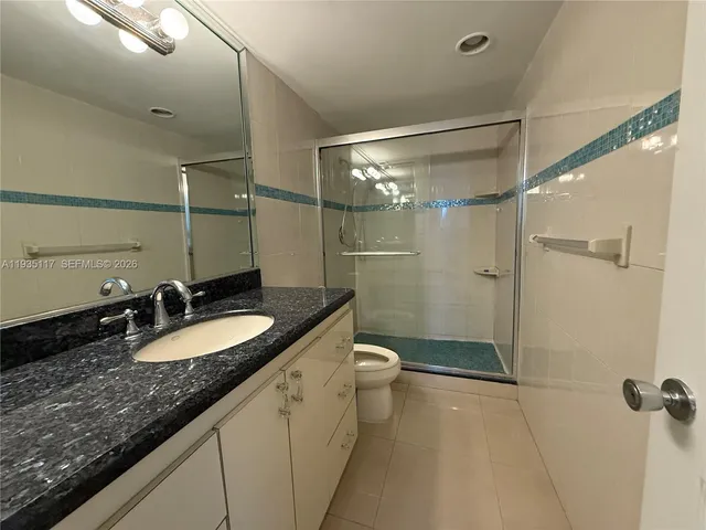 a bathroom with a granite countertop sink a toilet a mirror and shower