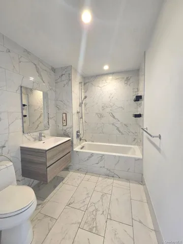 a bathroom with a bathtub shower sink mirror and toilet