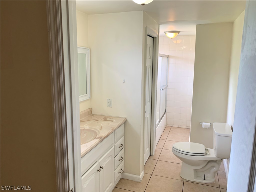 301 East Penn Road Lehigh Acres, FL 33936 - Photo 9 of 25 a bathroom with a granite countertop toilet a sink and a mirror