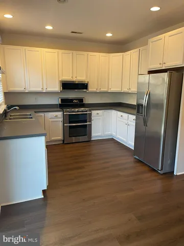 a kitchen with granite countertop a refrigerator and a stove top oven