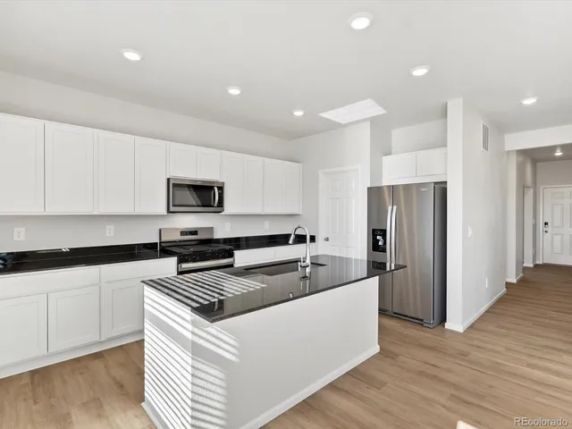 a kitchen with stainless steel appliances a refrigerator a sink and white cabinets