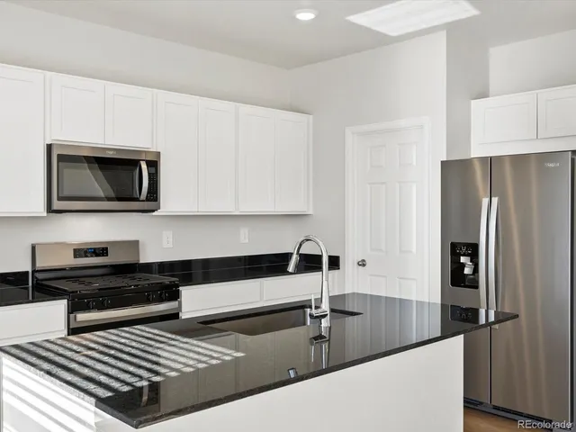 a kitchen with stainless steel appliances granite countertop a refrigerator a stove and a sink