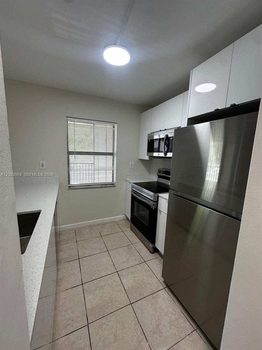 3400 Foxcroft Road, Unit 301 Miramar, FL 33025 - Photo 29 of 72 a kitchen with a refrigerator a stove a microwave and a window