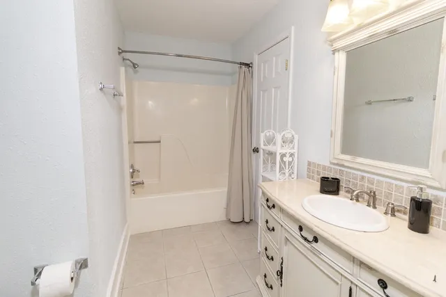 a bathroom with a granite countertop sink a mirror and a bathtub