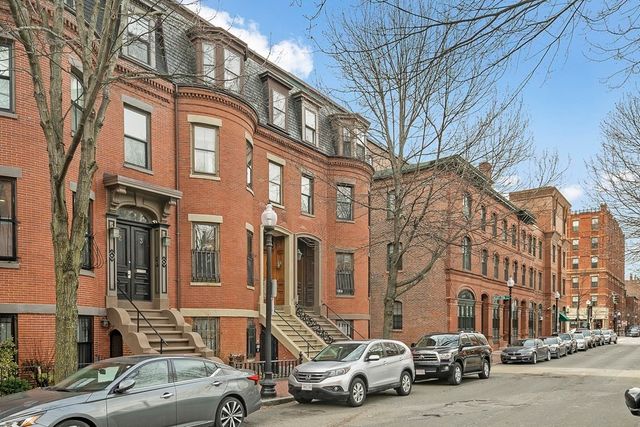 a city street lined with parked cars and buildings
