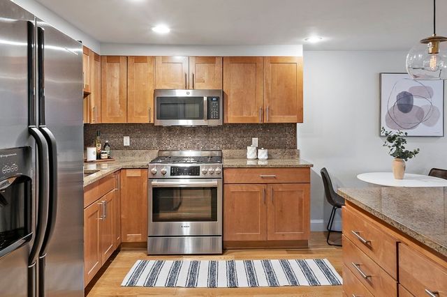 a kitchen with stainless steel appliances granite countertop a sink stove refrigerator and cabinets