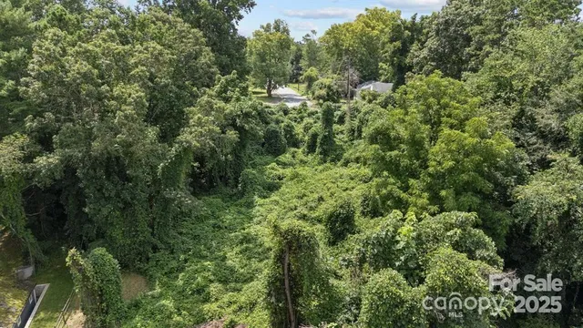 an aerial view of residential house with outdoor space and trees all around