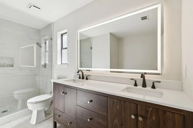 a bathroom with a double vanity sink toilet and shower
