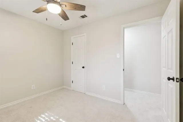 an empty room with a chandelier fan and closet
