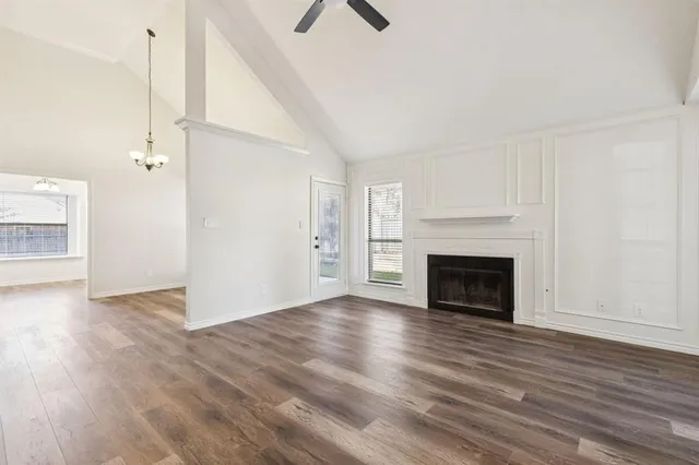 an empty room with wooden floor fireplace and windows
