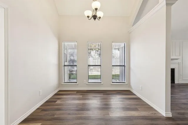 a view of an empty room with window and wooden floor