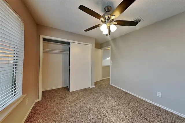 an empty room with closet and a chandelier fan