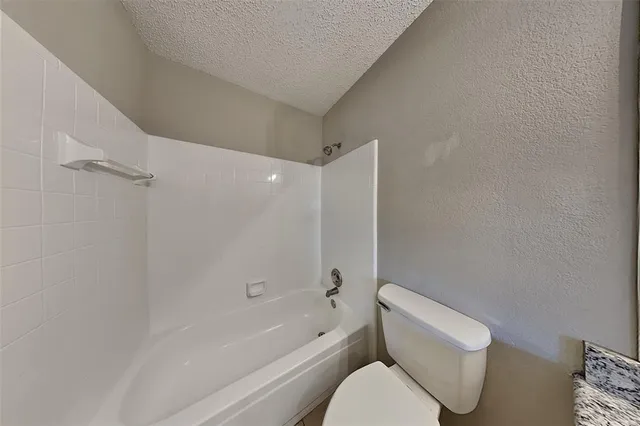 a white toilet sitting next to a bath tub