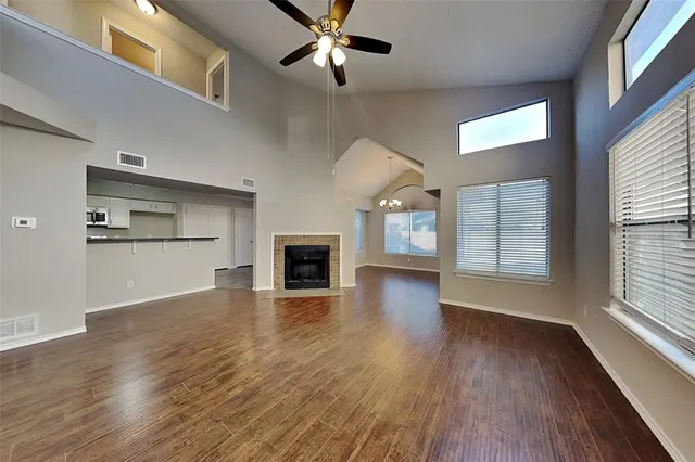 an empty room with wooden floor fireplace and windows