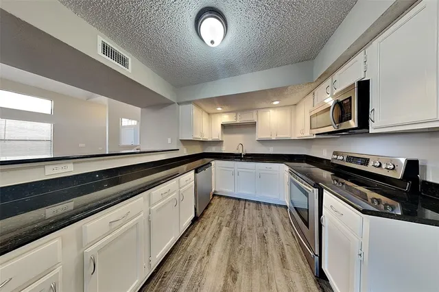 a large kitchen with stainless steel appliances granite countertop a stove a sink and a microwave