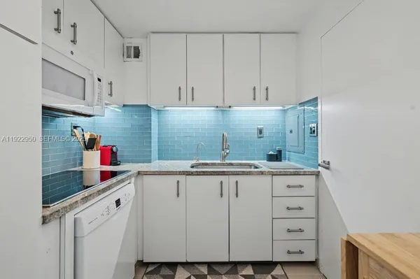 a kitchen with white cabinets and sink