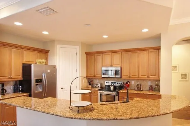 a kitchen with kitchen island granite countertop a stove sink cabinets and refrigerator