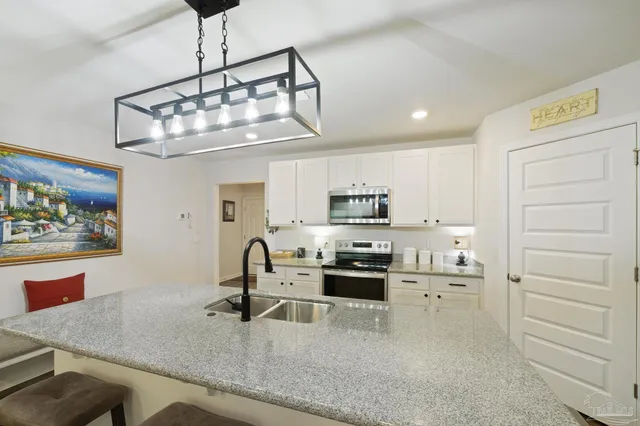 a large kitchen with a counter space a sink appliances and cabinets