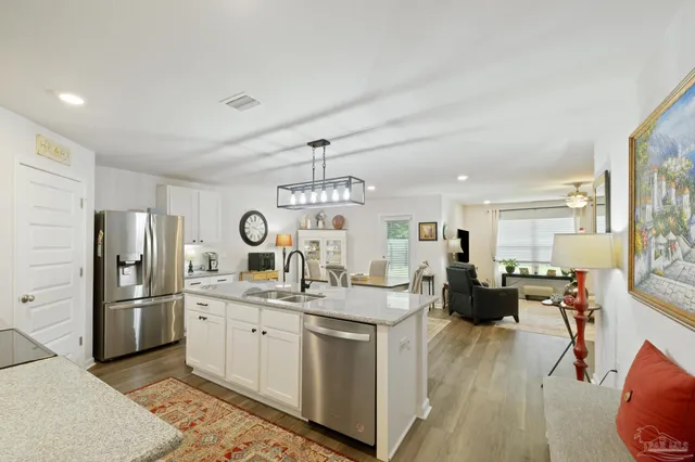 a kitchen with kitchen island granite countertop a sink a counter space appliances and cabinets