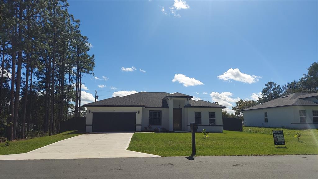 5984 Southwest 128th Street Road Ocala, FL 34473 - Photo 2 of 23 a front view of a house with a yard and garage