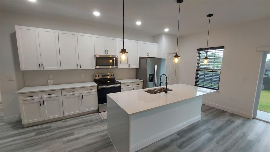 5984 Southwest 128th Street Road Ocala, FL 34473 - Photo 9 of 23 a kitchen with refrigerator cabinets and wooden floor