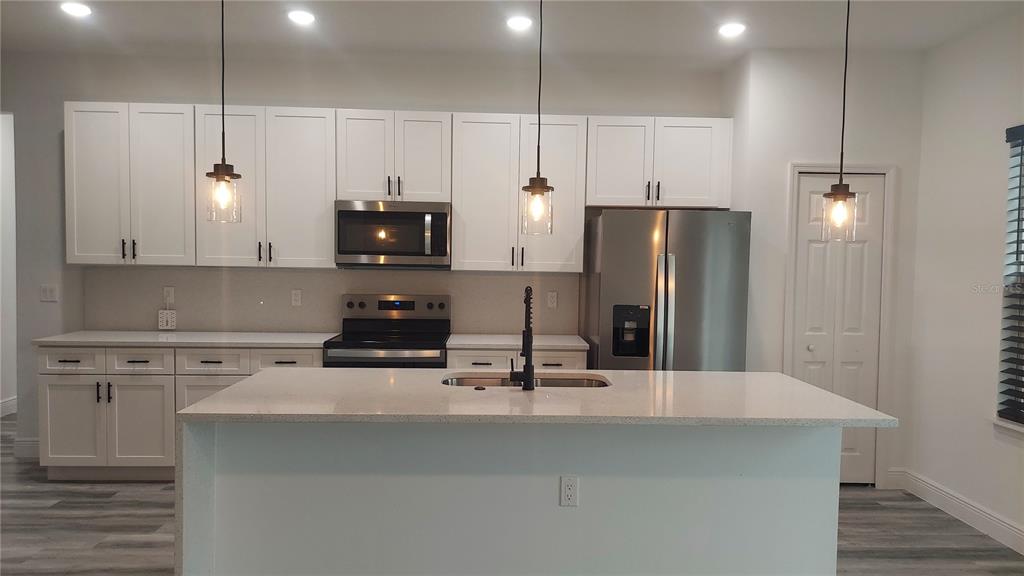 5984 Southwest 128th Street Road Ocala, FL 34473 - Photo 10 of 23 a kitchen with stainless steel appliances a stove a refrigerator and a sink with wooden floor
