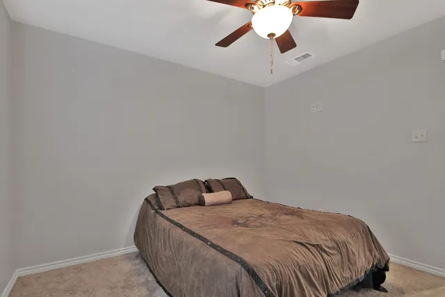a bedroom with a bed and a chandelier fan