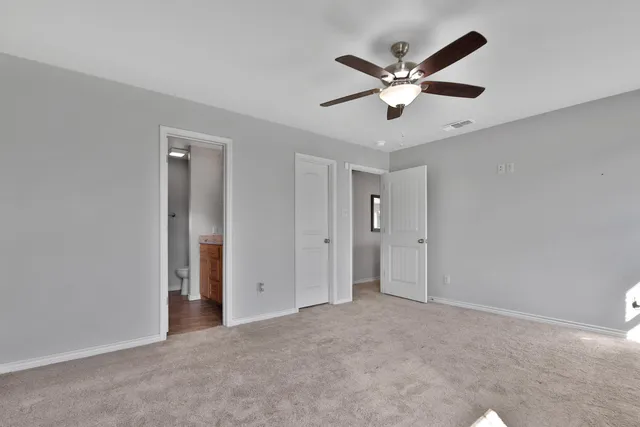 a view of an empty room with window and ceiling fan