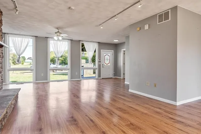 an empty room with wooden floor and windows