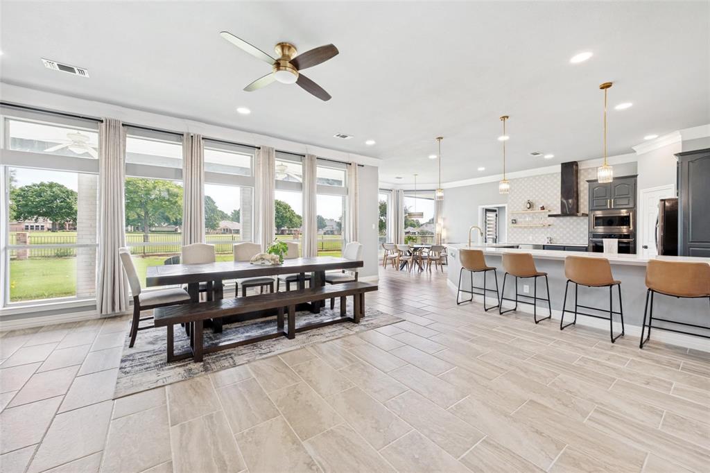 818 Riviera Drive Mansfield, TX 76063 - Photo 19 of 24 Spacious open-concept living area featuring light-toned tile flooring, an integrated kitchen island with pendant lighting, a built-in oven, and a large dining space with expansive windows