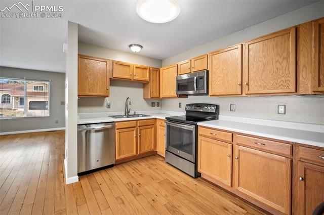 5223 Rondo Way Colorado Springs, CO 80911 - Photo 2 of 3 Kitchen with sink, stainless steel appliances, and light hardwood / wood-style floors