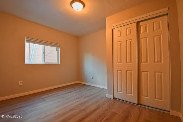 an empty room with wooden floor and closet area