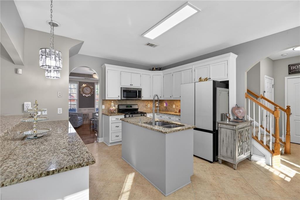 4817 Pepper Tree Lane Douglasville, GA 30135 - Photo 11 of 65 a kitchen with stainless steel appliances granite countertop a refrigerator a stove top oven a sink dishwasher a refrigerator and white cabinets with wooden floor