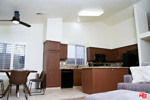 a living room with stainless steel appliances kitchen island granite countertop furniture and a refrigerator