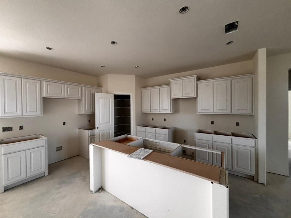 Kitchen featuring white shaker-style cabinetry, a central island, recessed lighting, and a pantry with built-in shelving