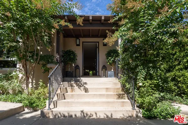 a view of a house with potted plants and a tree