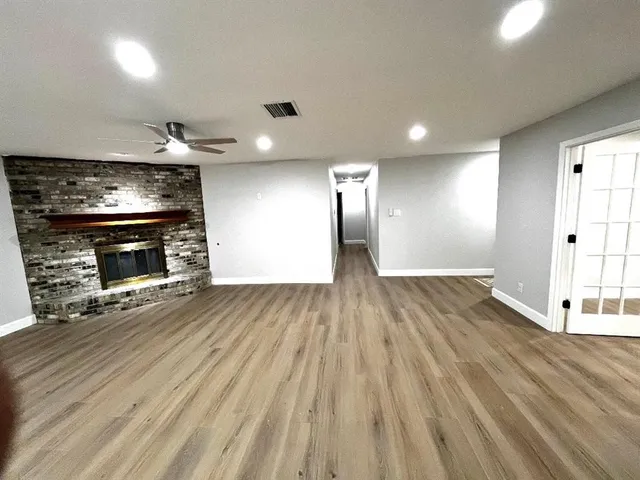 an empty room with wooden floor fireplace and windows