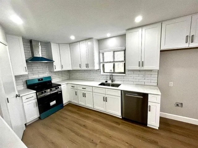 a kitchen with a sink cabinets stainless steel appliances and a window