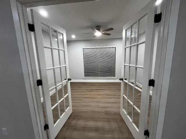 a view of an empty room with wooden floor and a window