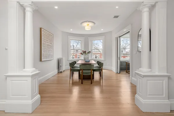 a dining room with wooden floor a chandelier a glass table and windows
