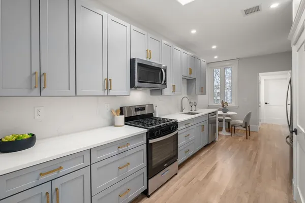 a kitchen with granite countertop cabinets stainless steel appliances a sink and wooden floor