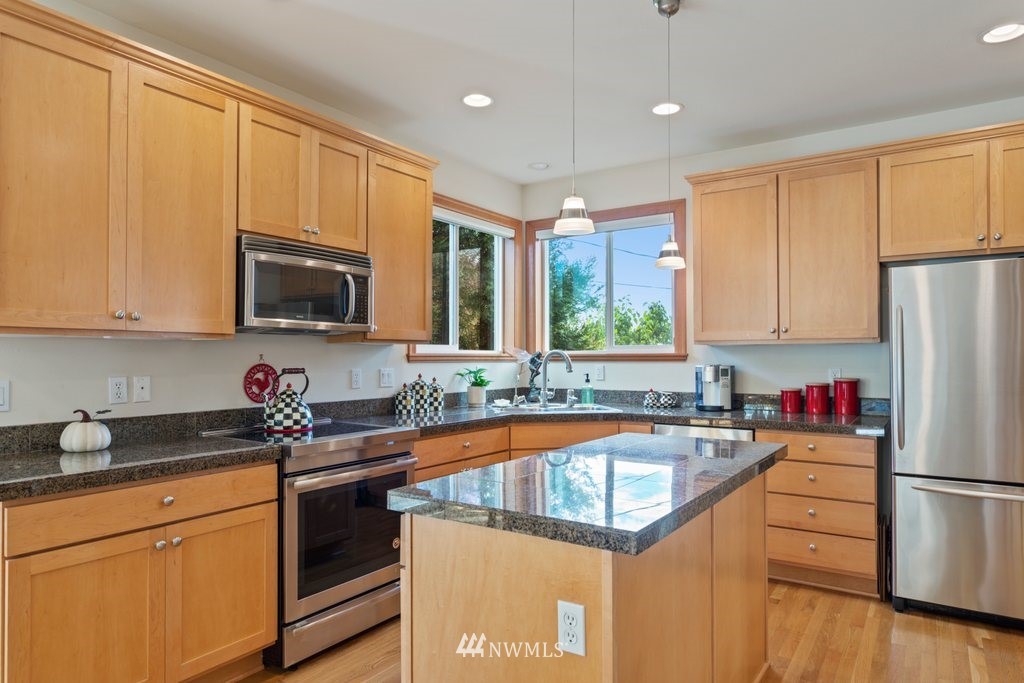 2013 Northeast 15th Street Renton, WA 98056 - Photo 8 of 29 a kitchen with stainless steel appliances granite countertop a stove top oven a sink dishwasher a dining table and chairs with wooden floor