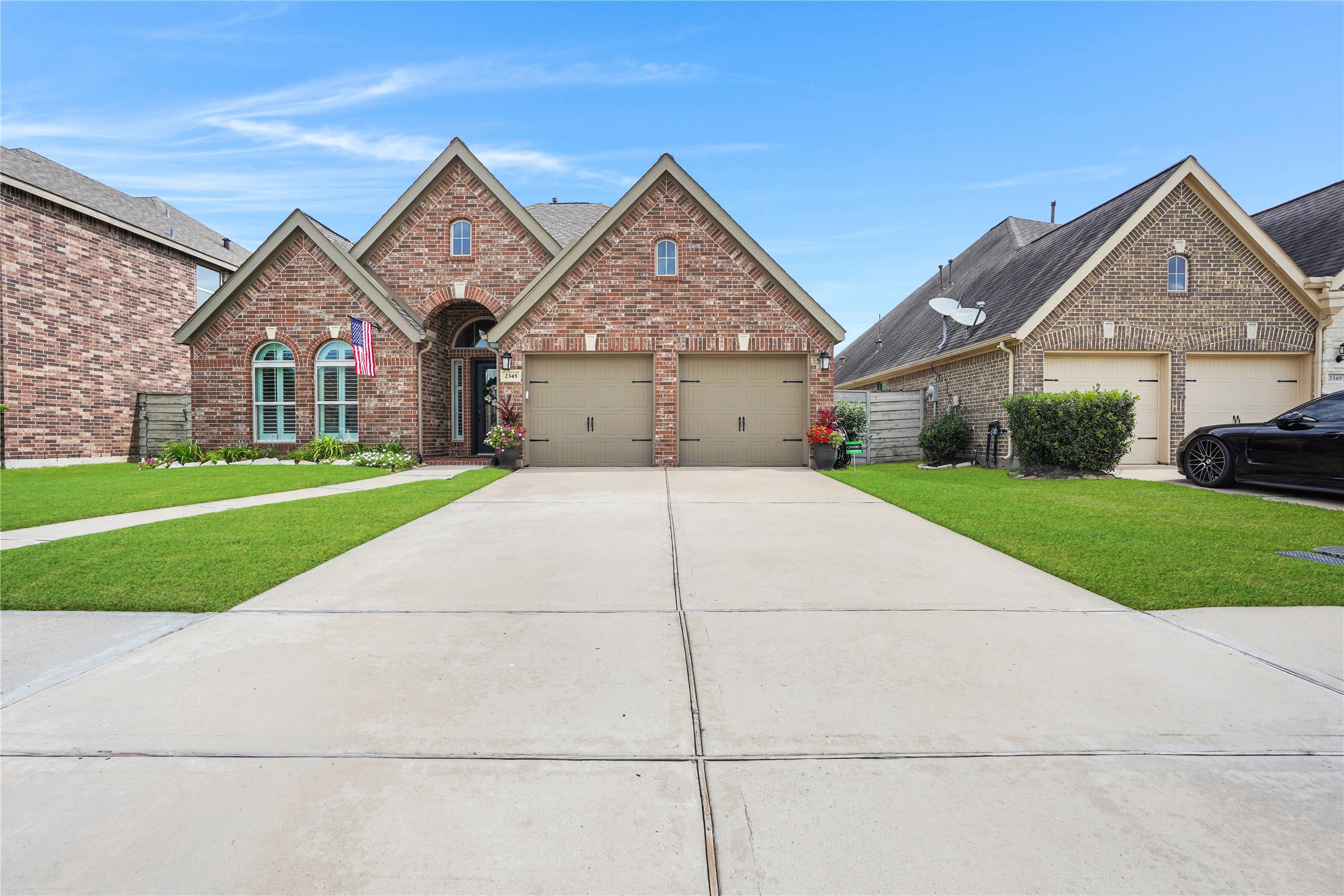2345 Redwood Ridge Trail Manvel, TX 77578 - Photo 4 of 39 This photo shows a charming brick house with a well-maintained lawn and a spacious driveway leading to a two-car garage. The entrance has an arched doorway, and there are decorative windows, enhancing its curb appeal.