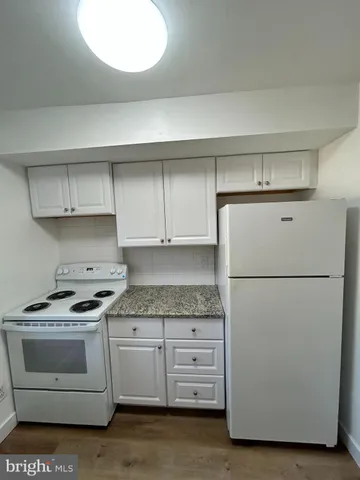 a kitchen with granite countertop a white stove a sink and a refrigerator