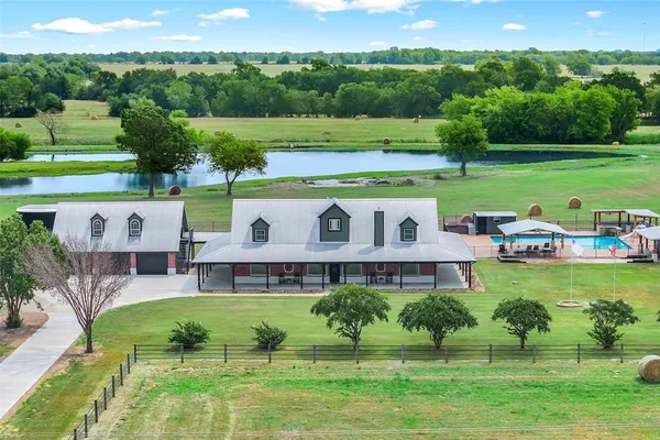 a view of a big house with a big yard and large trees