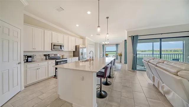 a kitchen with stainless steel appliances kitchen island granite countertop a refrigerator a stove top oven a sink dishwasher and white cabinets with wooden floor