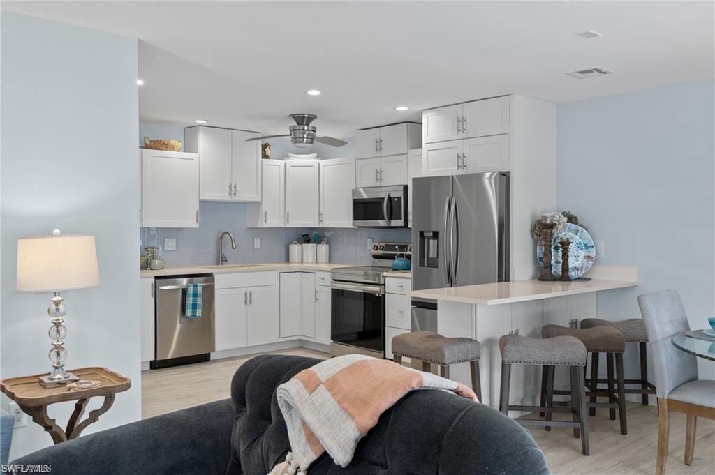 1435 Curlew Avenue, Unit 3 Naples, FL 34102 - Photo 16 of 28 a kitchen with stainless steel appliances a stove a sink dishwasher a refrigerator oven and a dining table with chairs