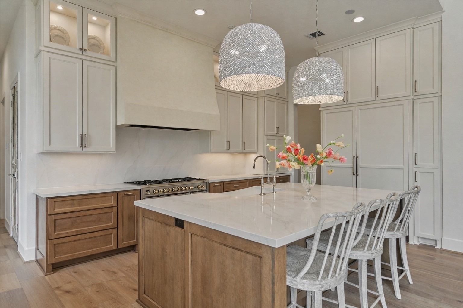 7715 Morgans Pond Court Spring, TX 77389 - Photo 5 of 50 Large island with quartz countertops, Thermador paneled appliances, ILVE 6-burner range with griddle & double oven, pot filler, lighted glass display cabinetry, brushed gold hardware and designer lighting.