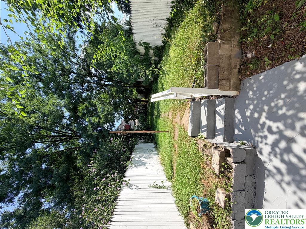 718 Ferry Street Easton, PA 18042 - Photo 26 of 37 Green landscaping and a white privacy fence line a pathway to the residence.